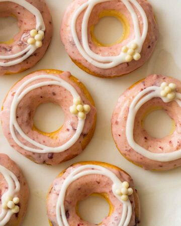 Close up of baked cherry doughnuts with cherry and vanilla glaze and white chocolate crispy balls.