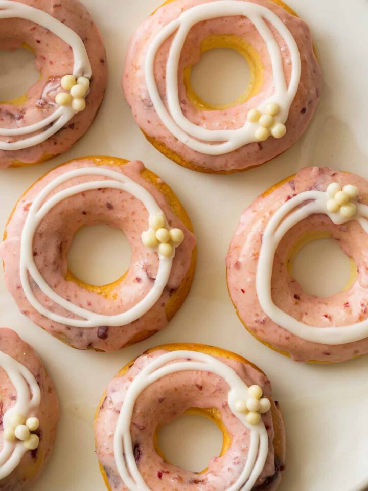 Close up of baked cherry doughnuts with cherry and vanilla glaze and white chocolate crispy balls.