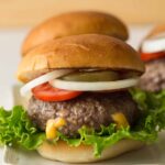 A close up of a juicy lucy burger with all the fixings.