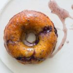 A close up of a baked blueberry doughnut with glaze.