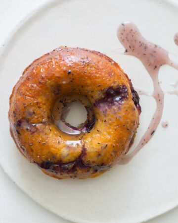A close up of a baked blueberry doughnut with glaze.