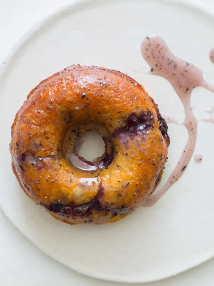 A close up of a baked blueberry doughnut with glaze.