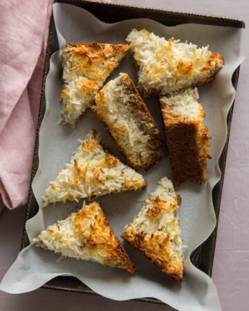 Several triangle cut pieces of coconut oat bars in a pan.