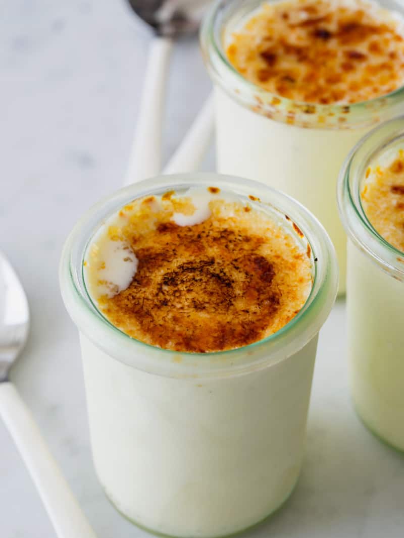 A close up of jars of creme brûlée frozen custard with spoons.