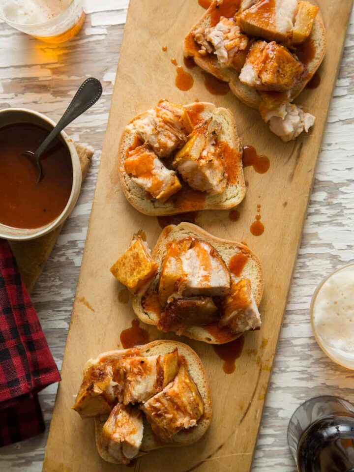 Crispy grilled pork belly with sweet and tangy vinegar BBQ sauce on bread.