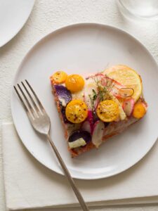 A piece of stacked salmon on a white plate with a fork.