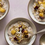 Bowls of chia seed pudding topped with fruit and shredded coconut with a spoon.