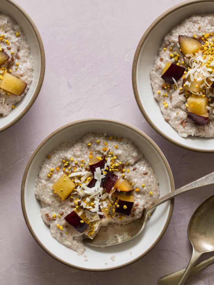 Bowls of chia seed pudding topped with fruit and shredded coconut with a spoon.