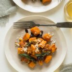 Plates of sweet potato gnocchi with fried sage dried cherries and toasted hazelnuts with a fork.