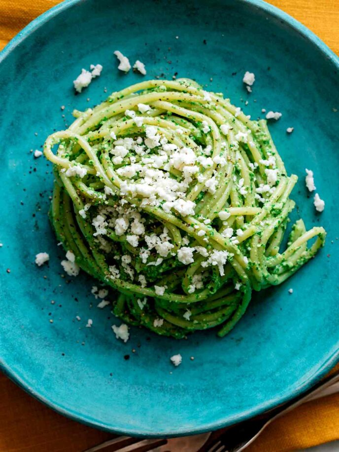 Tallarines verde on a blue plate piled in a heap.