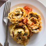 A plate of lasagna roll ups with a fork.