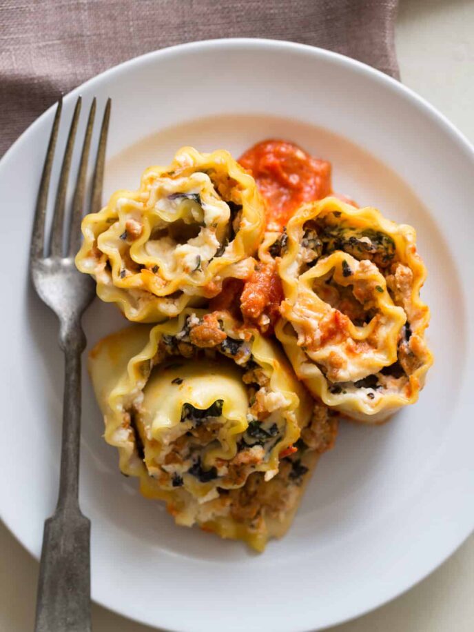 A plate of lasagna roll ups with a fork.