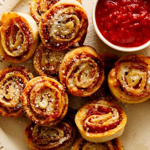 A close up of pizza wheels with a ramekin of marinara sauce on a plate.