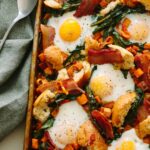 A close up of a savory breakfast pan with linens and a spoon.