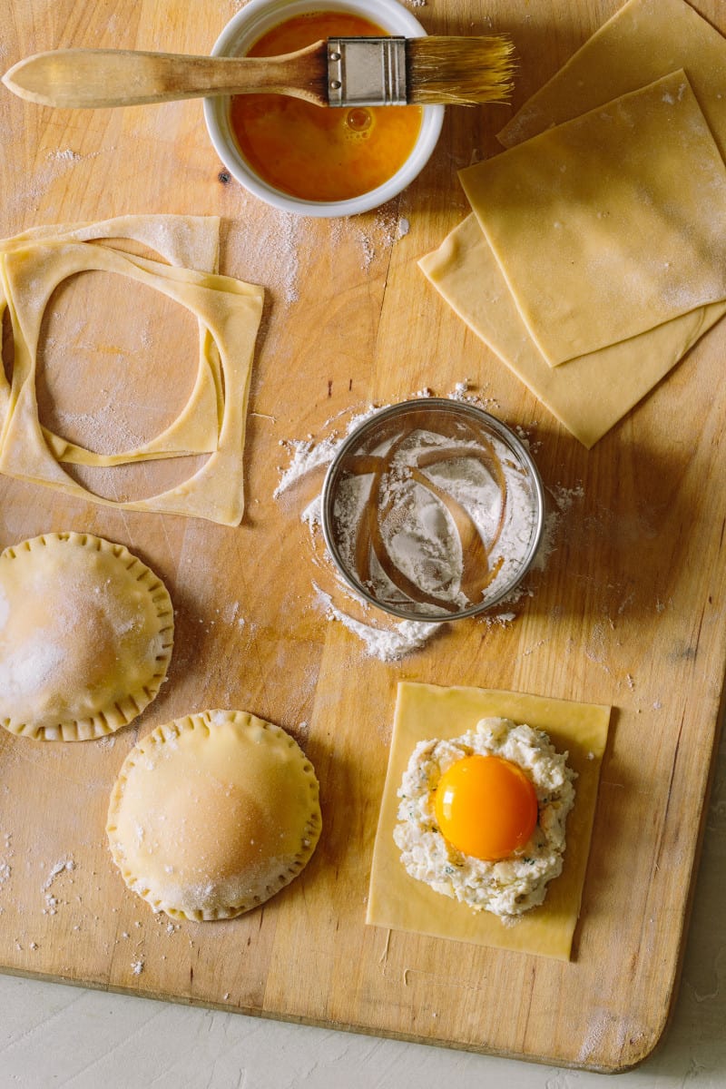 Process to make chicken and tarragon poached yolk stuffed ravioli on a cutting board.