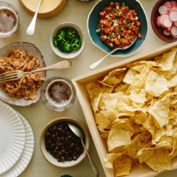 Chips in a tray and toppings in different bowls for DIY nacho bar.