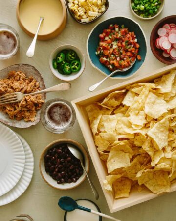 Chips in a tray and toppings in different bowls for DIY nacho bar.