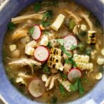 White bean chili in a blue bowl with toppings.