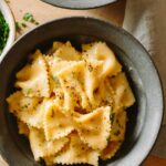 A close up of farfalle with creamy white bean and roasted garlic sauce in a bowl.