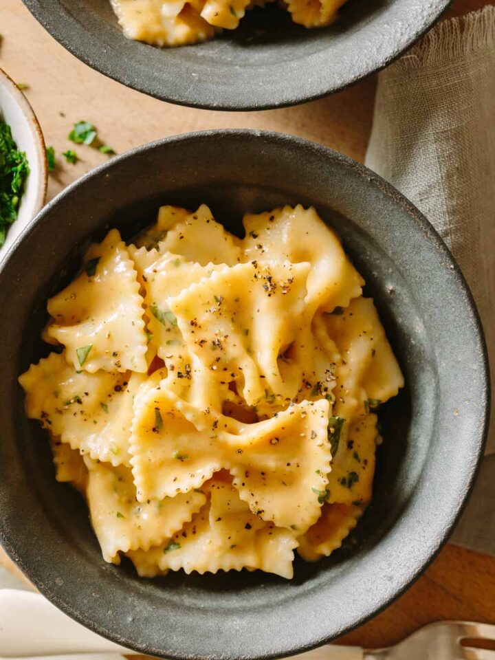 A close up of farfalle with creamy white bean and roasted garlic sauce in a bowl.