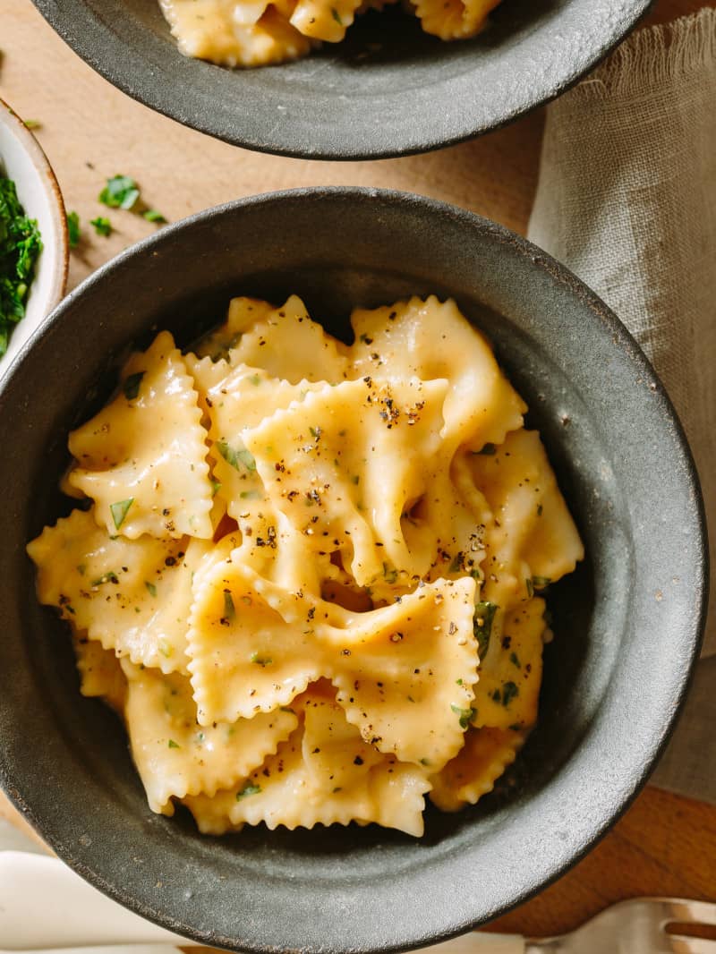 A close up of farfalle with creamy white bean and roasted garlic sauce in a bowl.