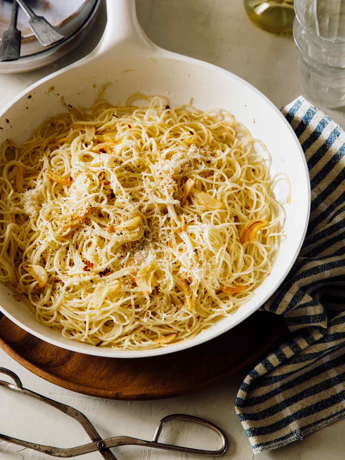 Capellini pasta in a skillet with parmesan on top. 