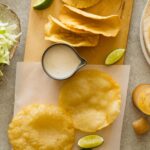 DIY hard and puffy corn tortillas, flat and folded on a cutting board.