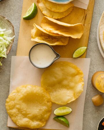 DIY hard and puffy corn tortillas, flat and folded on a cutting board.