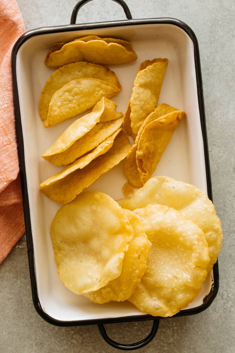 DIY hard and puffy corn tortillas, flat and folded on a platter.