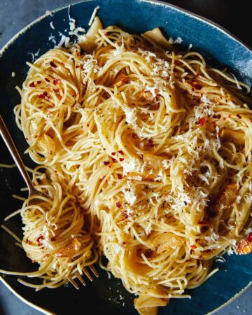 A close up of capellini with garlic lemon and parmesan with a fork.