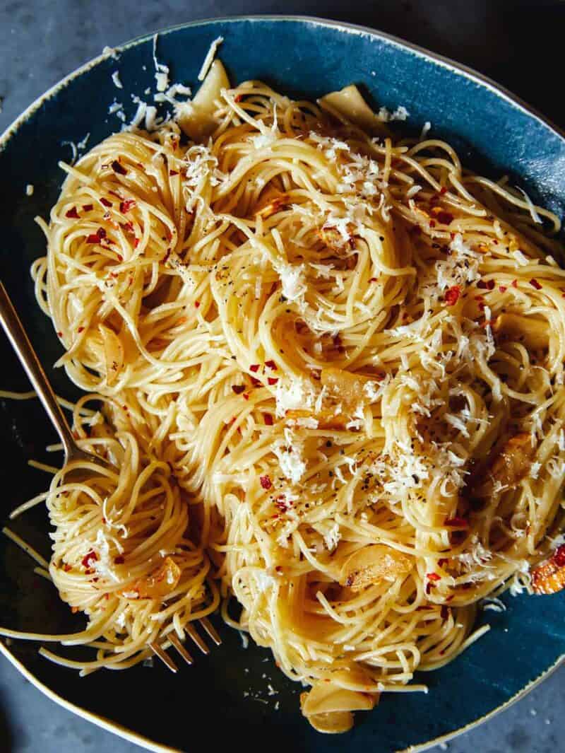 A big bowl of garlic and lemon capellini pasta with a fork in it. 