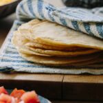 DIY hard and puffy corn tortillas, flat and folded on a cutting board.