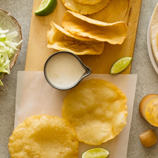 DIY hard and puffy corn tortillas, flat and folded on a cutting board.