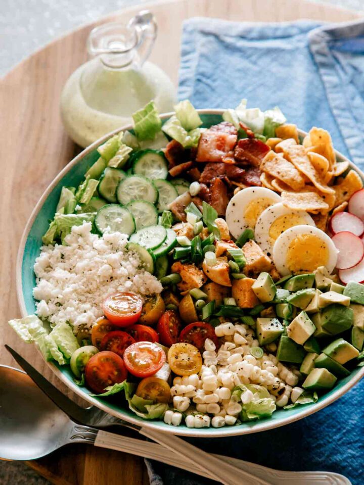 A plate of southwestern style cobb salad with cilantro ranch dressing on the side.