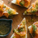 Slices of DIY gravlax with whole grain mustard sauce drizzled and on the side.