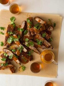 Mango habanero glazed spare ribs garnished with cilantro and extra glaze on the side.