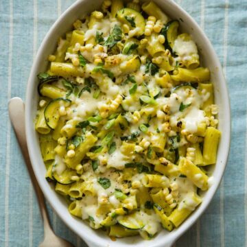 Baked chicken rigatoni with sweet corn, zucchini, and a roasted poblano béchamel with a spoon.