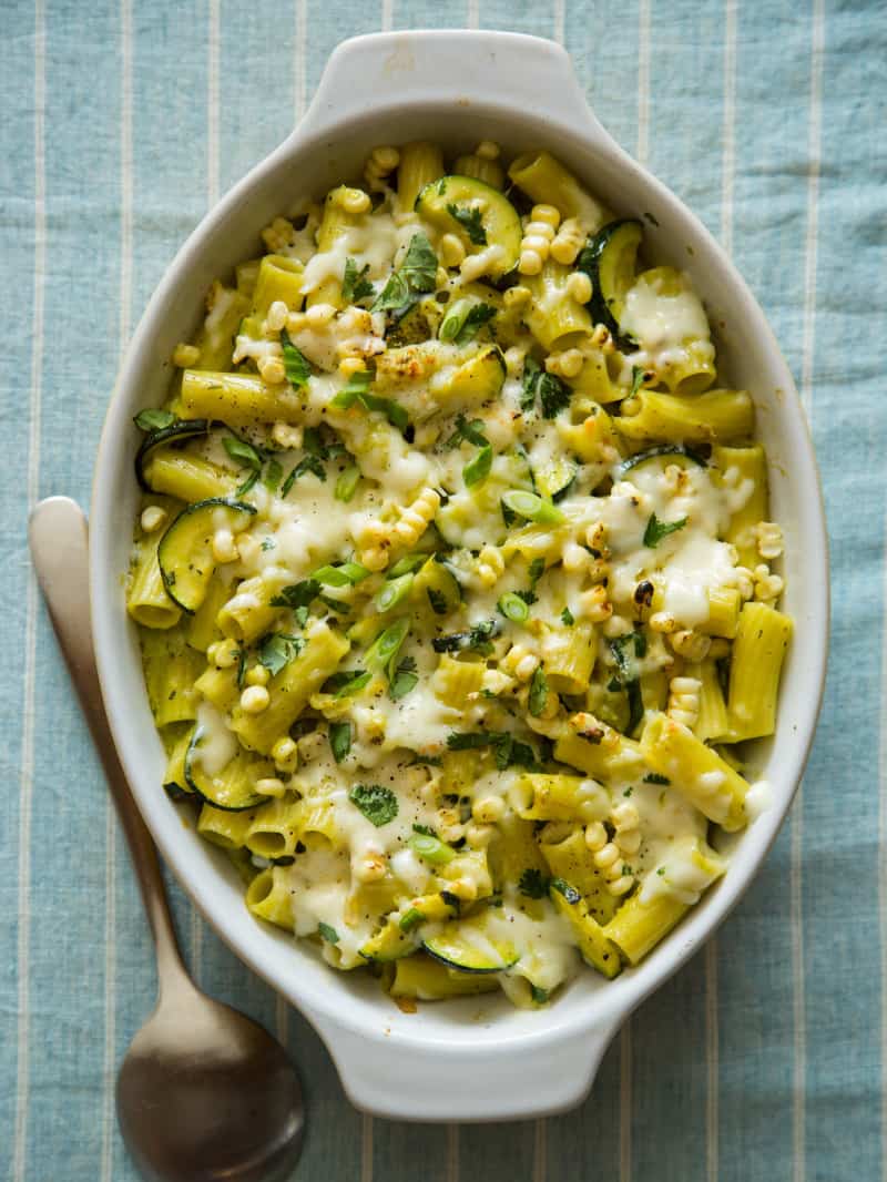 Baked chicken rigatoni with sweet corn, zucchini, and a roasted poblano béchamel with a spoon.