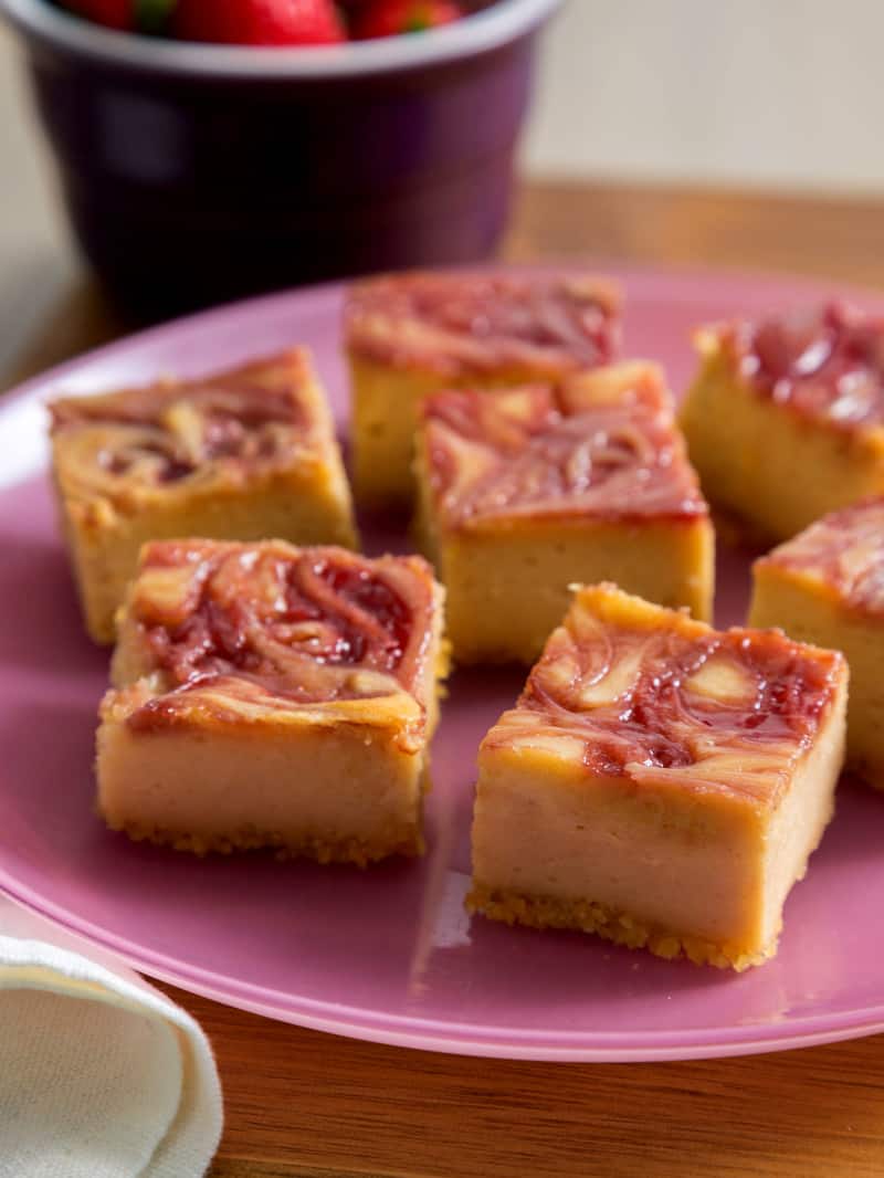 Peanut butter and jelly cheesecake bars with potato chip crust on a plate.