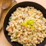 A bowl of Hawaiian style macaroni salad with a wooden spoon.