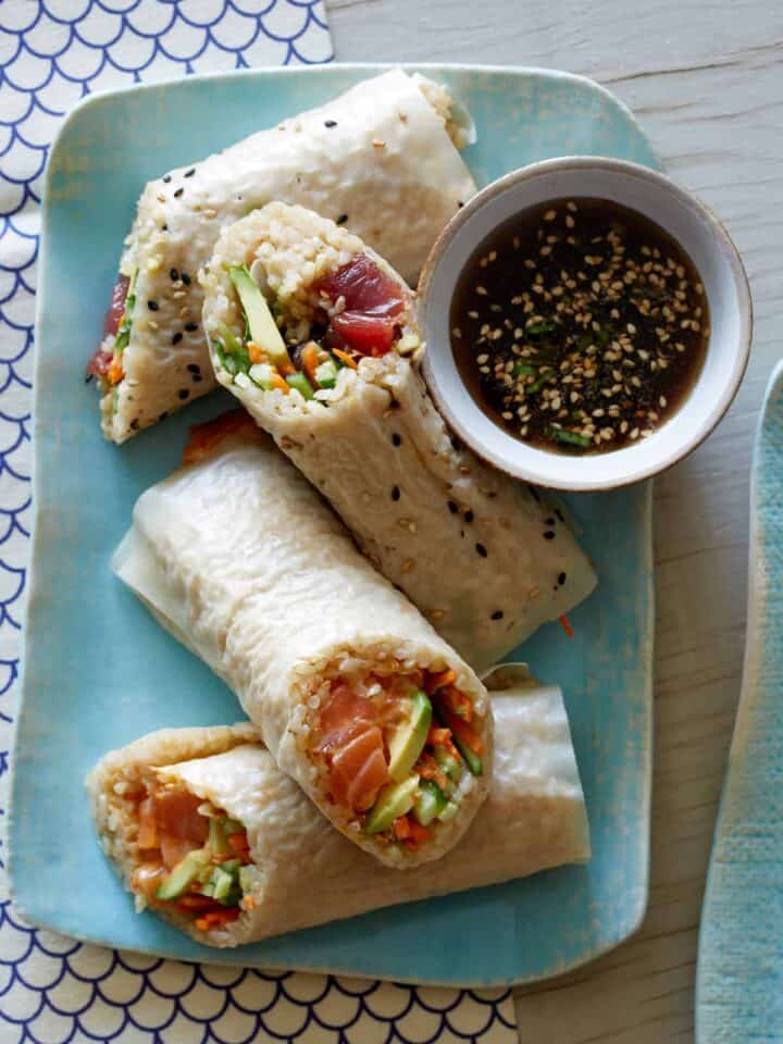 A plate of poke burritos with dipping sauce on the side.