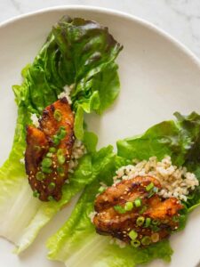 Korean style marinated spicy pork belly on brown rice and a lettuce cup.