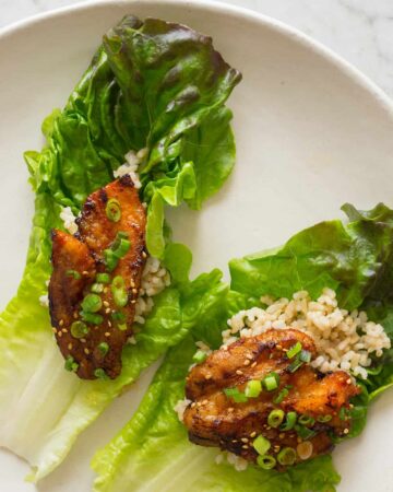 Korean style marinated spicy pork belly on brown rice and a lettuce cup.