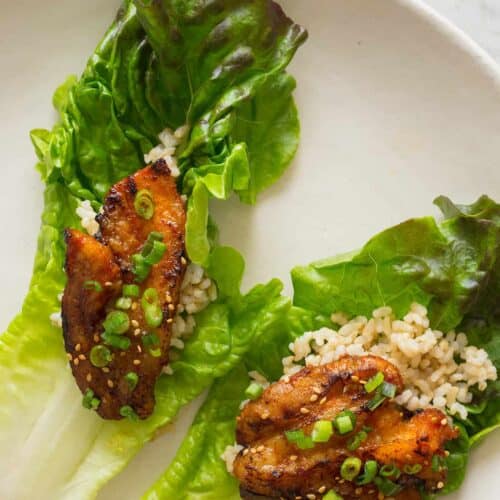 Korean style marinated spicy pork belly on brown rice and a lettuce cup.