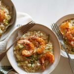 Bowls of sweet corn risotto with Cajun shrimp and forks.