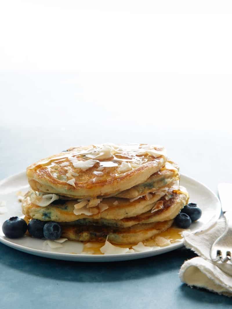 A stack of brown sugar, coconut, blueberry pancakes with a fork.