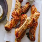 Pizza stuffed breadsticks on a wooden cutting board next to a plate.