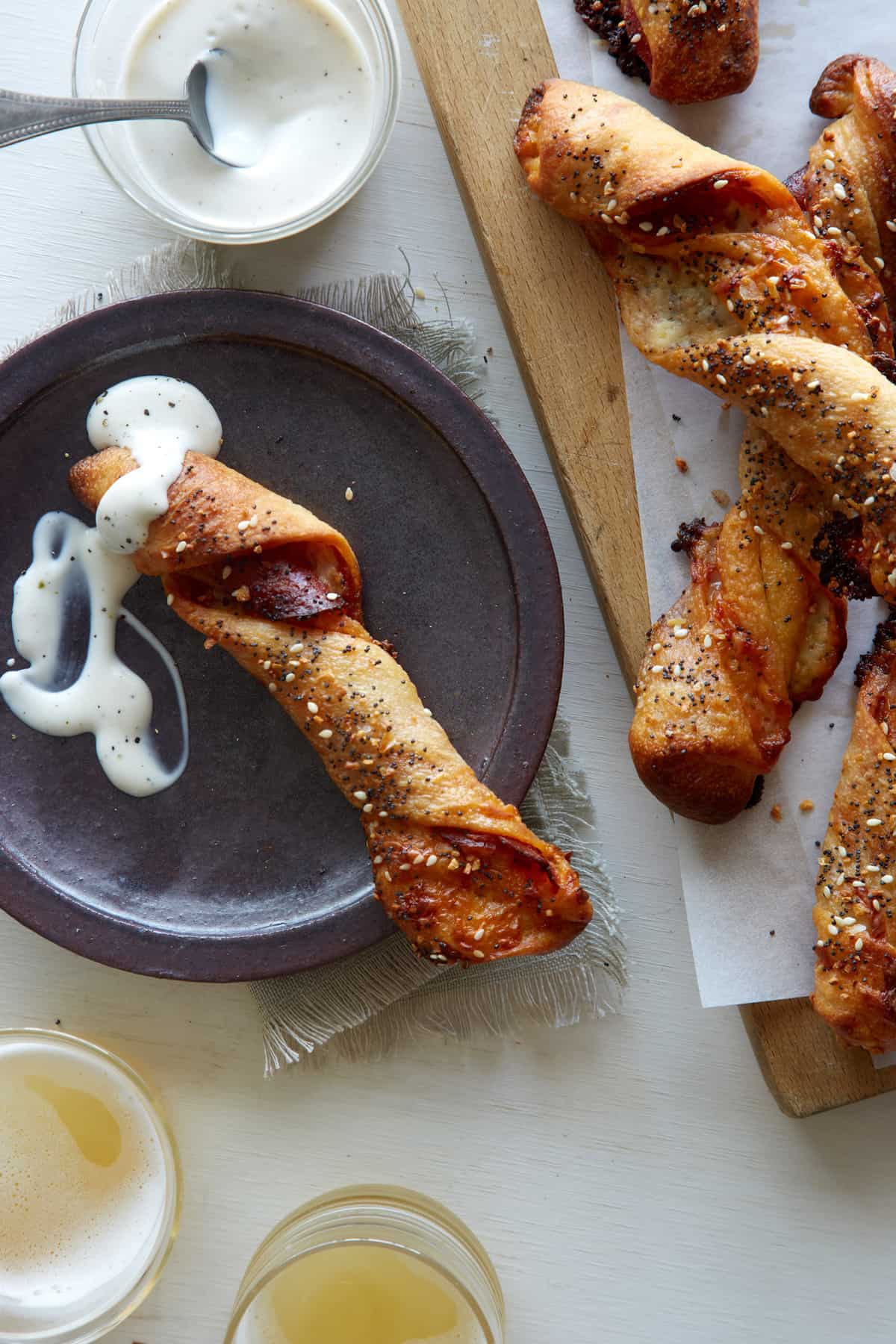 Pizza stuffed breadsticks on a wooden cutting board and on a plate with sauce.