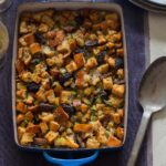 A pan of fig, herb, and sausage stuffing with a serving spoon.