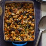 A pan of fig, herb, and sausage stuffing with a serving spoon.
